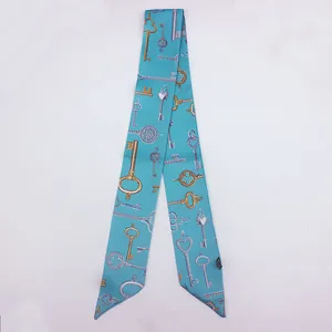 Detalle de un pañuelo de seda azul menta con motivos de llaves doradas y plateadas