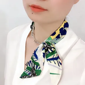 Détail d'un anneau de foulard mors argenté avec un foulard en soie à imprimé tropical
