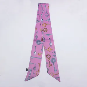 Detalle de un pañuelo de seda rosa con patrón de llaves vintage y elegantes puntas sesgadas