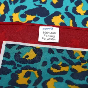 Detail of leopard print silk-feeling scarf featuring a red rolled edge and care label