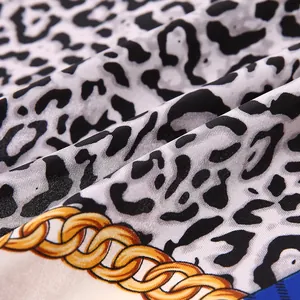 Detailed macro view of leopard print silk scarf with golden chain patterns and silky texture