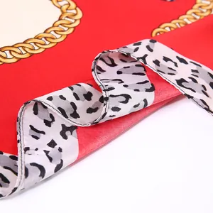 Macro shot of red silk scarf showing golden chain patterns and leopard print edge