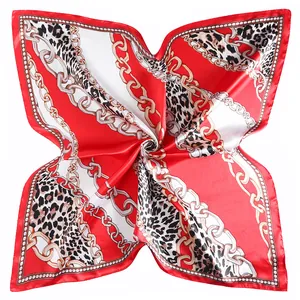 Macro shot of 90cm leopard print silk scarf featuring golden chain details and red blocks