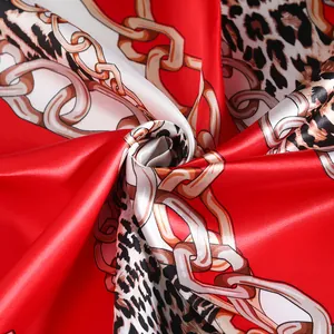 Macro detail of silk-like scarf featuring luxury leopard print and golden chain motifs