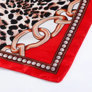 Close-up of leopard print silk scarf featuring golden chains and red borders