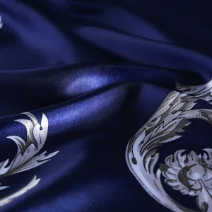 Close-up of luxury navy blue silk scarf featuring intricate white Baroque pattern details