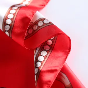 Close-up of red silk scarf showing leopard chain patterns and satin texture