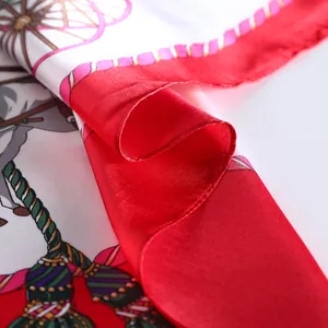 Close-up of silk scarf showing red borders and equestrian patterns with luxury texture