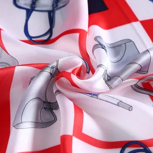 Detail showing the glossy silk satin texture and chic handbag pattern on the square scarf