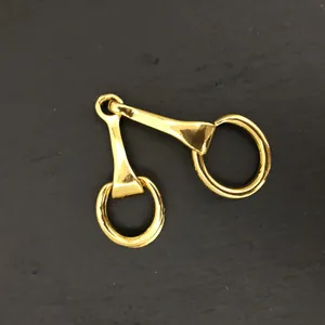 Vue macro du mors de cheval en métal doré montrant la finition brillante et le double anneau
