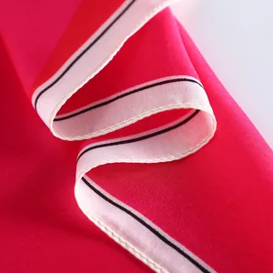 Macro shot of red silk scarf showing fine rolled hem stitching and glossy fabric texture