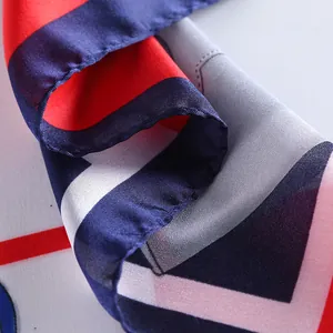 Detail of silk-like square scarf featuring modern geometric patterns and rolled hem edges