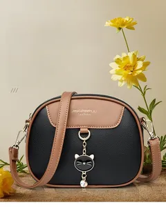 Detail of bicolor crossbody bag with cat charm and gold hardware on pebble leather