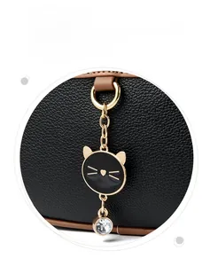 Macro shot showing textured lychee leather and a cat-shaped pendant with a crystal drop