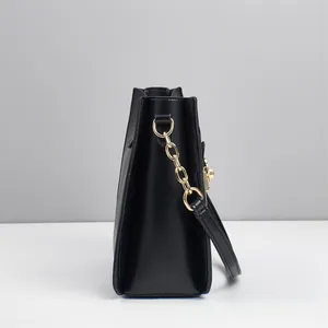 Detail view of the black leather bag side with glossy gold chain strap hardware