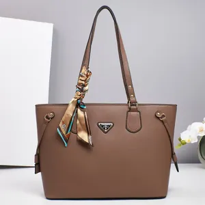 Macro detail of brown litchi leather tote with silk scarf and triangular metal plate
