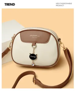 Detail view of the two-tone lychee grain faux leather handbag with cat pendant