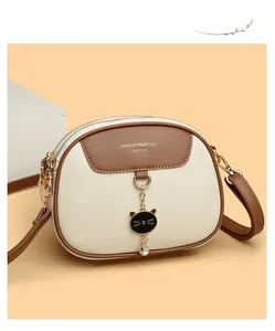 Close-up of beige and brown leather round bag with cat pendant and textured finish