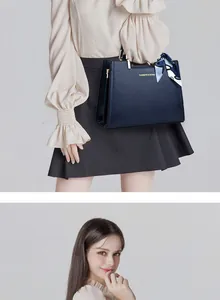 Detail of navy blue pebble leather handbag with gold logo and decorative floral scarf