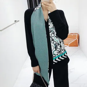 Detail van elegant zwart vest met V-hals en asymmetrische zijden sjaal met geometrische kettingprint