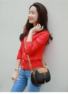 Detail of a crossbody bag with black lychee leather, brown trim, and cat-shaped charm