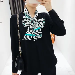 Detail van zwarte chiffon blouse met een geometrisch bedrukte zijden sjaal als strik