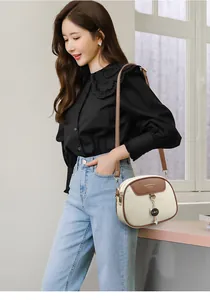 Close-up of white round crossbody bag with cat pendant and jingpinpiju lettering