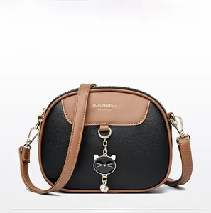 Detail of cross-body bag with lychee texture leather and a gold cat chain pendant