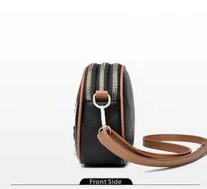 Detail view of the triple-zipper leather round crossbody bag with adjustable shoulder strap