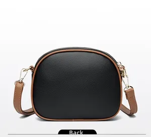 Detail view of the black lychee pattern leather back with brown trim on crossbody bag