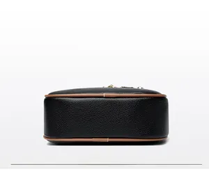Detailed bottom view of black pebbled leather bag with tan piping and stitching