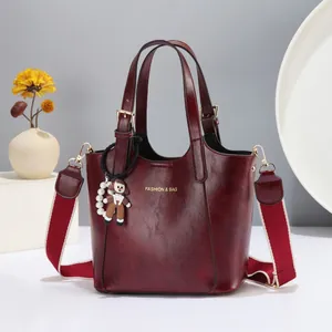 Detail of burgundy leather tote with gold logo and stylish red-white striped strap