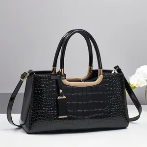 Close-up of black crocodile embossed handbag with golden U-shaped hardware and orchid decoration