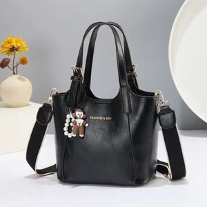 Detail of black leather bucket bag with gold lettering and colorful wide shoulder strap