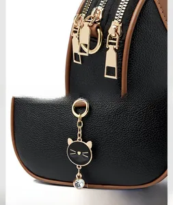 Detail of black pebbled leather texture, gold zippers and a rhinestone cat charm