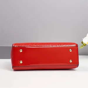 Detail view of the red patent leather bag base featuring gold-tone protective metal feet