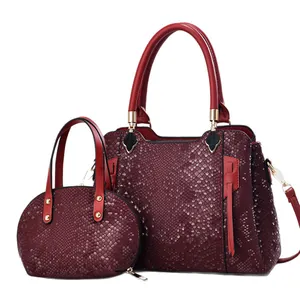 Deep wine red snakeskin embossed tote bag set with golden hardware on white background
