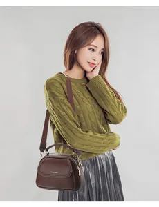 Close-up of brown litchi pattern leather bag with gold hardware and wide strap