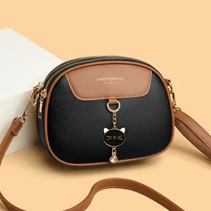 Chic black and brown leather round shoulder bag with cat pendant on geometric background