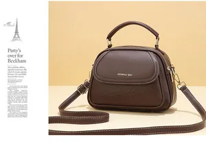 Detail of dark brown leather handbag with gold zippers and embossed circular patterns