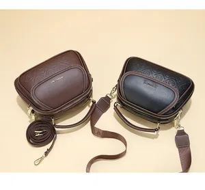 Detail view of multi-layer leather handbags with textured embossing and wide fabric straps