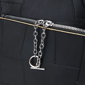 Détail du sac en cuir matelassé noir avec fermeture éclair argentée et pendentif en T