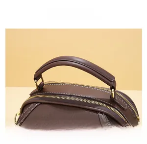 Detail shot of brown leather handbag with fine lychee texture and curved top handle