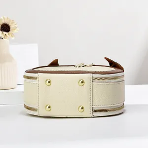 Detail of cream pebbled leather mini bag with double zipper and gold rivet accents