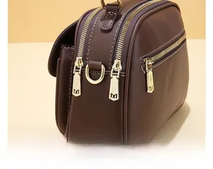 Close-up of premium dark brown faux leather bag featuring three gold-tone zippers with M-logo