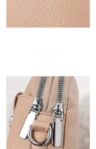 Detail of beige litchi grain leather texture and shiny silver hardware zipper closure