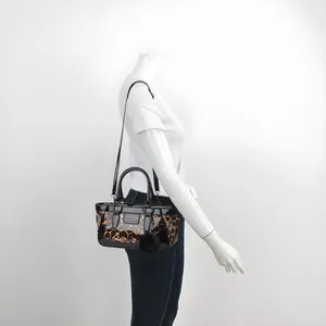 Detail view of leopard print tote bag with black patent leather trim and plush charm