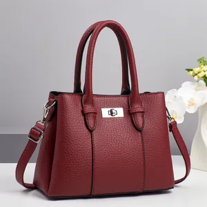 Detail of burgundy lychee pattern leather handbag featuring a silver twist lock and strap