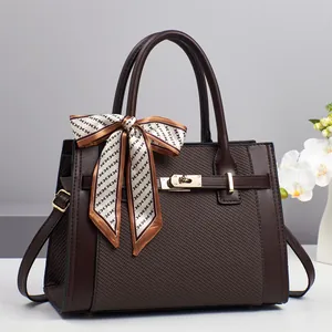 Detail of coffee tote bag with diamond lattice pattern, gold hardware and printed scarf