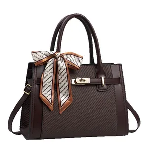 Fashionable dark brown leather handbag with contrast textures and silk scarf on handle